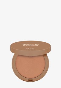 Bronceador con acabado brillante en un compacto redondo. Tono marrón claro con un brillo sutil. El envase presenta una tapa sólida color tostado y marca visible.