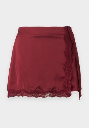 Bordowa satynowa spódnica z koronkową lamówką po jednej stronie, z dopasowaną talią i lekkim efektem zakładki. Gładka tekstura, o długości do kolan.