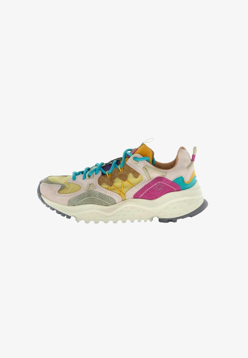 Zapatilla deportiva de caña baja con paneles multicolores vibrantes, cordones azules, suela gruesa y texturizada, y materiales mixtos en tonos beige, rosa, azul verdoso, amarillo y gris.