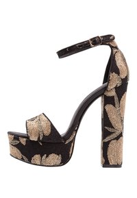 Zapatos de tacón negro con plataforma y patrón floral dorado, con un tacón alto grueso y una correa en el tobillo con un hebilla. Suela antideslizante.
