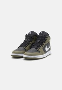 High-top sneakers in olive green and black leather, featuring a white Nike swoosh, black laces, and a perforated toe design.