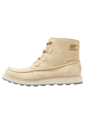 Beiger Wildleder-Stiefel mit Schnürung vorne, robuster Sohle und wasserfestem Sorel-Logo an der Seite.