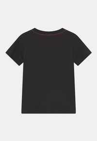 Svart bomull T-shirt med korta ärmar, med rund halsringning och kontrasterande röd söm längs axelsömmen.