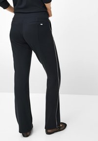 Zwarte broek met een rechte pijp, voorzien van een witte zijstreep, twee achterzakken en een elastische tailleband voor comfort.