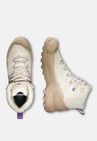 Jasno beżowe buty trekkingowe z teksturowanym wykończeniem, gumową podeszwą, fioletowymi akcentami sznurowadeł oraz miękkim wykończeniem dla wygody.