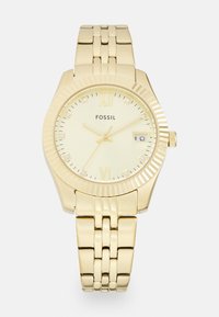 Złoty zegarek Fossil z teksturowaną kopertą, znacznikami w postaci cyfr rzymskich i wyświetlaczem daty. Posiada ogniwowy metalowy bracelet oraz minimalistyczny cyferblat.