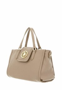 Bolso de mano de cuero beige con asas dobles, herrajes dorados y un emblema decorativo en la solapa frontal. Textura suave, diseño estructurado.