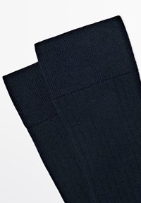 Mørkeblå ribbede sokker med et glat, struktureret bånd øverst og et blødt, strækbart materiale for komfort og pasform.