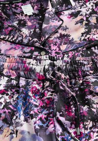Ziedu raksts audums purple, rozā, melnā un baltā krāsā ar pogātām apkaklēm, elastīgu jostasvietu un stringa detaļām.