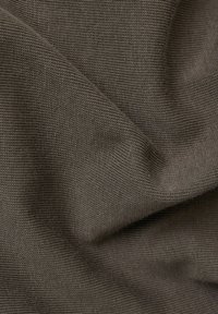 Tela marrón con un patrón texturizado y tejido. El material es suave y se drapea fácilmente, mostrando pliegues y arrugas en la superficie.