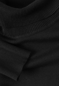 Schwarzer Strickpullover mit hohem, geripptem Rollkragen und weichem Material; die Ärmel sind leicht umgeschlagen und haben eine glatte, gleichmäßige Naht.