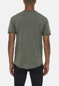 Olivenfarbene Kurzarm-T-Shirt mit Rundhalsausschnitt, rohen Kanten und abgerundetem Saum. Hergestellt aus weichem, strukturiertem Stoff.