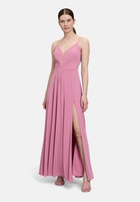 Długa różowa sukienka z głębokim dekoltem w kształcie litery V, cienkimi ramiączkami i rozporkiem do uda; wykonana z miękkiego, zwiewnego materiału o delikatnym połysku.