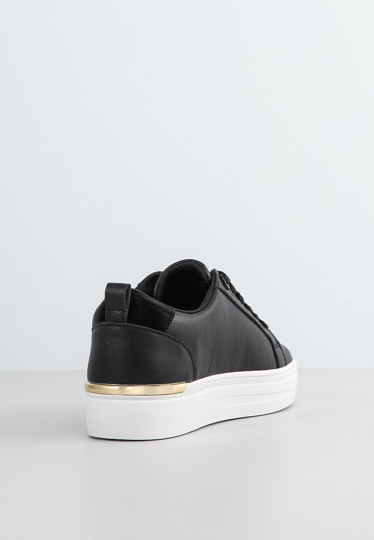 Baskets en cuir noir avec semelle blanche, présentant une touche d'or sur le talon. Texture lisse avec une forme arrondie et un design classique à lacets.