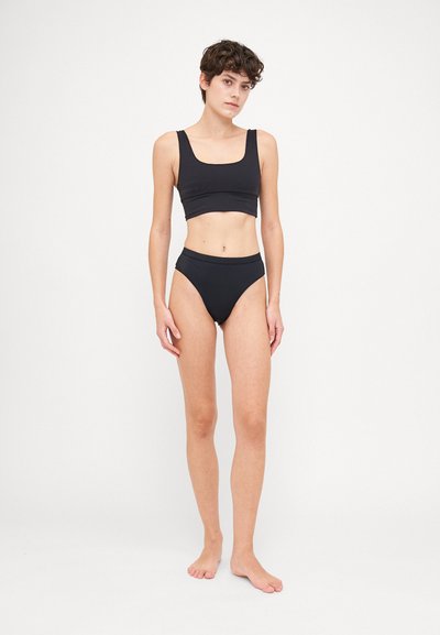 Melnā īsā topiņa un augsto jostasvietu bikini apakšdaļa, izgatavota no gludas auduma ar pieguļošu dizainu un tīrām līnijām. Nav rakstu vai rotājumu.