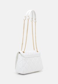 Quilted white faux leather handbag with gold chain and strap accents, featuring a trapezoidal shape and a seamless flap closure.