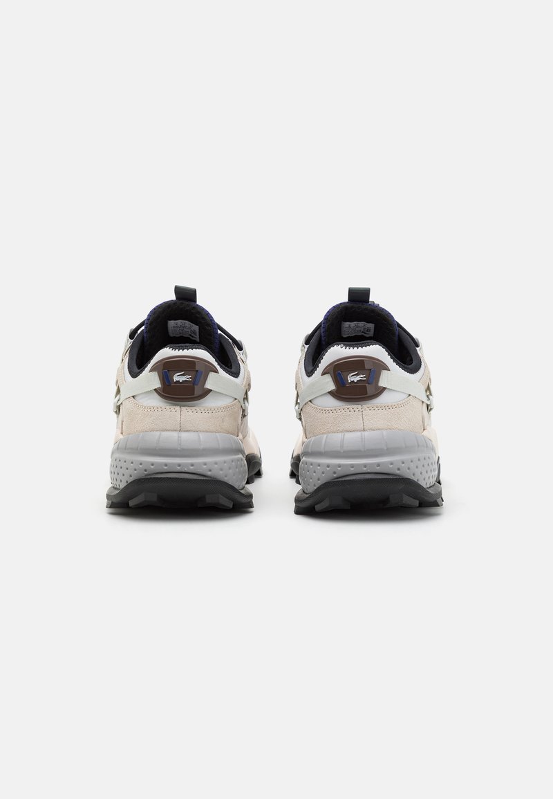 Scarpe da ginnastica sportive con una combinazione di colori beige e grigio, materiali in rete e suede, punta rotonda e suola in gomma nera texturizzata.