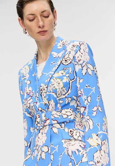 Blå blomsterblazer med store hvide og burgunder blomster mønstre, bælte i taljen og struktureret krave. Glat stoftekstur.
