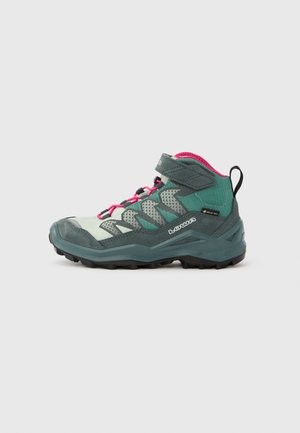 Mid-cut hiking boot in teal and gray, featuring pink accents, synthetic material, a textured upper, and rugged black sole for traction.
