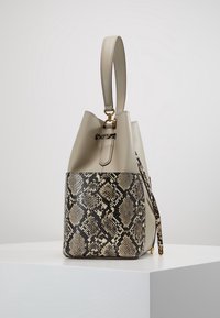 Beige läderhandväska med öppen topp, som har ett pytontryck på den nedre halvan och en detalj i guldfärgad spänne på handtaget.