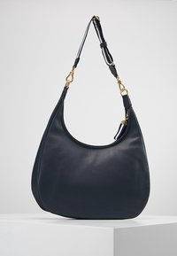 Marinblå läderhobo väska med en kurvad form, texturerad yta och en avtagbar rem med detaljer i guldton.