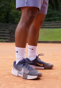 Nike Sportschuhe in Marineblau mit orangen Akzenten, strukturiertem Mesh-Obermaterial, weißer Sohle, Schn�ürsenkeln und kombiniert mit weißen gerippte Socken.