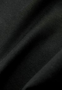 Sort stof med en glat tekstur, der har fine ribbede mønstre og bløde folder, som fremhæver materialets stræk og fleksibilitet.