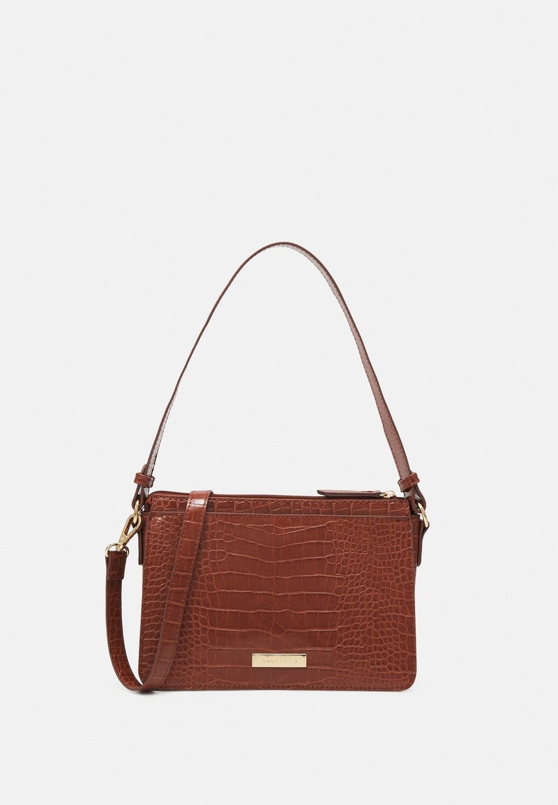 Sac à main en cuir texturé marron avec des anses courtes et longues, une quincaillerie dorée et une forme rectangulaire sur fond blanc.