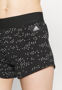 Czarne sportowe szorty wykonane z teksturowanej tkaniny, z białymi trójkątnymi wzorami, elastycznym pasem i logo Adidas z boku.