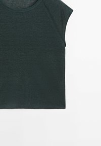 Top corto a maniche corte di colore verde scuro con scollo tondo e tessuto testurizzato. Design semplice e cropped con maniche raglan.