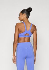 Sportbeha van lichtpaars stof met verstelbare bandjes en een uitgesneden achterkant. Gecombineerd met bijpassende, hooggetailleerde leggings in dezelfde kleur.