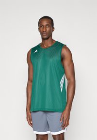 Zelená sieťová športová značková tričká s bielymi akcentovými pruhmi, kombinované so šedými šortkami s bielym lemom. Ľahká a priedušná tkanina.