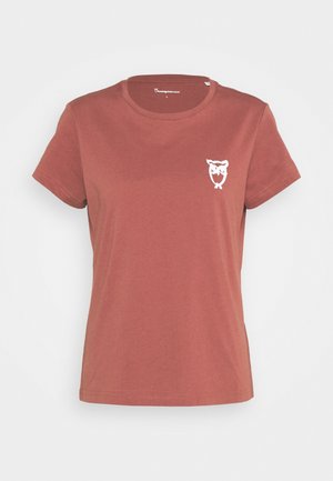 Camiseta de manga corta color óxido con escote redondo y un pequeño logo blanco de búho en el pecho izquierdo.