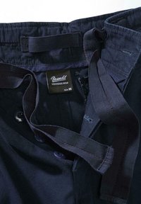 Marinblå byxor med knappstängning och justerbar midja, gjorda av ett mjukt tyg med en varumärkesetikett som anger storlek M.