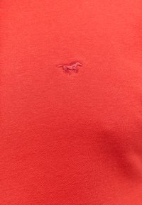 Czerwona dzianina z małym haftowanym logo konia w dopasowanym czerwonym kolorze, umieszczonym na środku powierzchni.