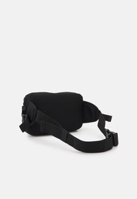 Czarna torba na ramię wykonana z teksturowanej siateczki, z zamkiem błyskawicznym i regulowanym paskiem z plastikową klamrą, zapewniającym pewne noszenie.