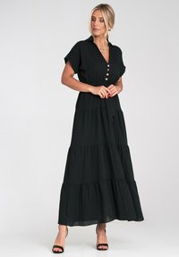 Czarna sukienka maxi z krótkimi rękawami, guzikiem, warstwowym designem i wiązaniem w talii. Gładki materiał o płynnej sylwetce.