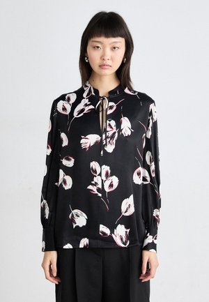 Black floral blouse with white and red tulip patterns, high neckline, tie closure, and long sleeves with gathered cuffs. Smooth fabric texture.