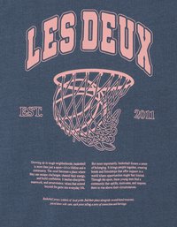 Μπλε σκούρο μπλουζάκι με γραφικό ροζ στεφάνι μπάσκετ. Το κείμενο κάτω από αυτό αναφέρεται στην κοινότητα και τις αξίες που συνδέονται με το μπάσκετ.