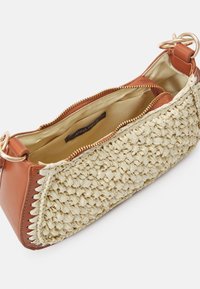Bolso de paja beige tejido con detalles en imitación cuero marrón, cremallera en tono dorado, forro interior en beige claro, que cuenta con una etiqueta de marca.