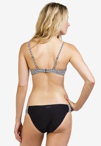 Zwarte bikini met een zigzagpatroon op de banden en zijkanten, met verstelbare banden en een eenvoudig ontwerp. Gladde textuur, aansluitende vorm.