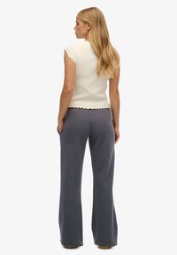 Korte mouw crème top met gegolfde randen, gecombineerd met grijze flared broek, met een soepele textuur en een ontspannen pasvorm.