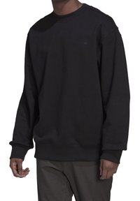 Svart crewneck sweatshirt med lös passform och ribbade ärmslut. Har en liten, broderad logotyp på bröstet. Mjuk, texturerad tyg.