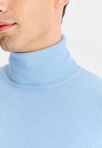 Jasnoniebieski sweter z golfem, wykonany z prążkowanej dzianiny. Posiada wysoki kołnierz oraz dopasowany krój, podkreślający gładką fakturę i elastyczność.