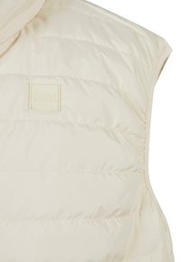 Cremfarbener ärmelloser Puffer-Weste mit gestepptem Muster und tonalem Markenlabel im Brustbereich. Weiches, leichtes Material.