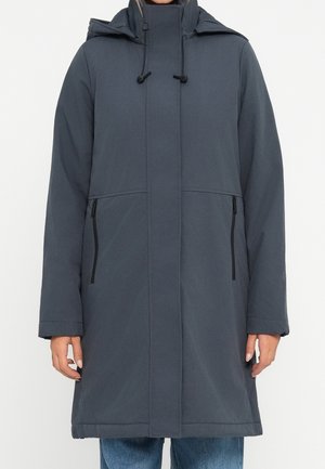 Długi ciemnoszary zimowy płaszcz z wysokim kołnierzem, kapturem, zamkiem błyskawicznym z przodu i zapinanymi na zamek bocznymi kieszeniami, noszony przez osobę w niebieskich dżinsach.