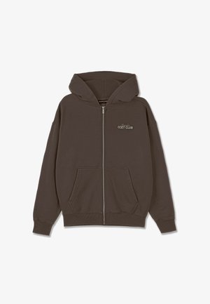Brauns zip-up kapuce, izgatavots no kokvilnas maisījuma, ar priekšējo kabatu, regulējamu kapuci un "Cozy Club" tekstu kreisajā krūtīs.
