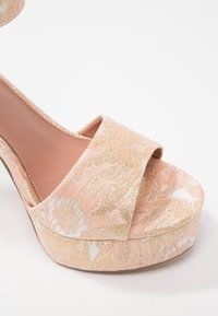 Pink and gold floral patterned high-heeled platform sandal with wide front strap and open toe on white background.