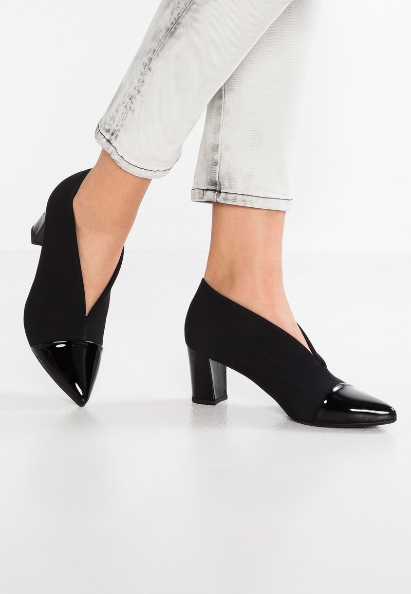 Chaussures à talons noires avec une tige extensible, présentant un bout pointu et des accents en vernis brillant. Les talons carrés offrent stabilité et confort.