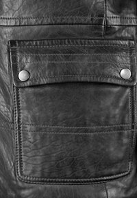 Zwarte leren jaszak met een klep die wordt vastgezet door twee metalen drukknoopjes en zichtbare stikdetails.